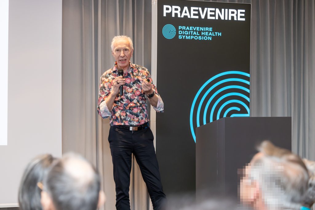 CEO spricht bei digital health symposion über Linked Care mit Mikrophon vor praevenire banner Rollup