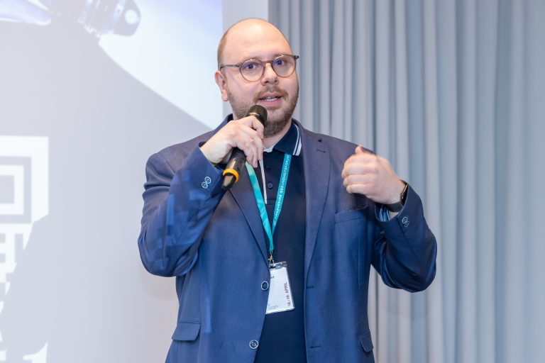 Mitarbeiter spricht mit Mikrophon beim digital health symposion über CAATS Software